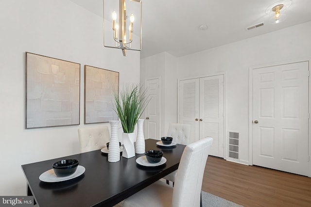 dining room with hardwood / wood-style floors and an inviting chandelier