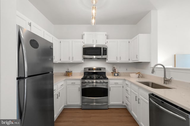 kitchen with white cabinetry, sink, light stone countertops, and appliances with stainless steel finishes