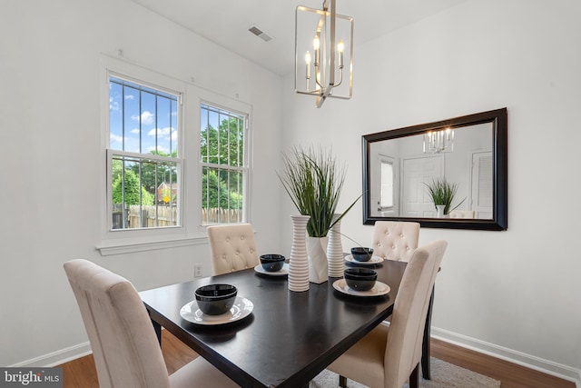 dining area featuring hardwood / wood-style flooring and an inviting chandelier