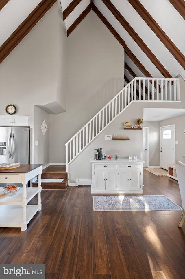 unfurnished living room featuring baseboard heating, high vaulted ceiling, and dark wood-type flooring