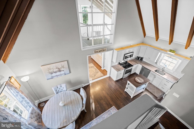 living room with beam ceiling, dark hardwood / wood-style floors, high vaulted ceiling, and sink