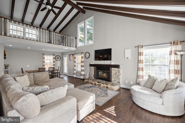 living room with a stone fireplace, ceiling fan, beamed ceiling, and dark wood-type flooring