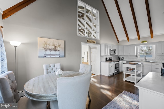 dining area featuring beam ceiling, sink, high vaulted ceiling, dark hardwood / wood-style floors, and a baseboard heating unit