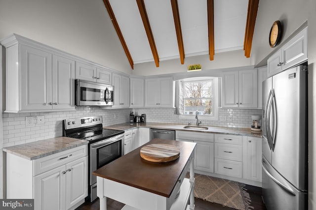 kitchen featuring beam ceiling, stainless steel appliances, white cabinetry, and sink