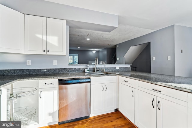 kitchen featuring dishwasher, sink, kitchen peninsula, light hardwood / wood-style flooring, and white cabinetry