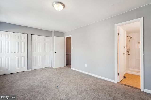 unfurnished bedroom with carpet, two closets, and ensuite bath