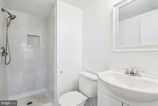 bathroom with vanity, toilet, and tiled shower