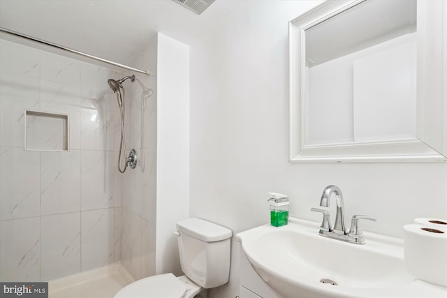 bathroom featuring tiled shower, vanity, and toilet