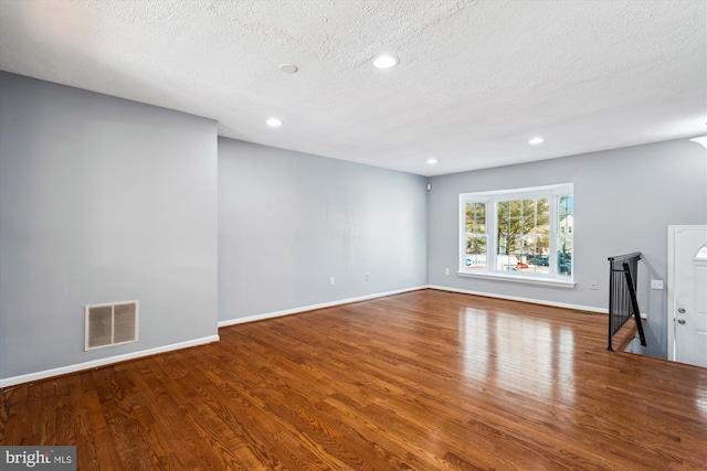 unfurnished living room featuring hardwood / wood-style floors and a textured ceiling