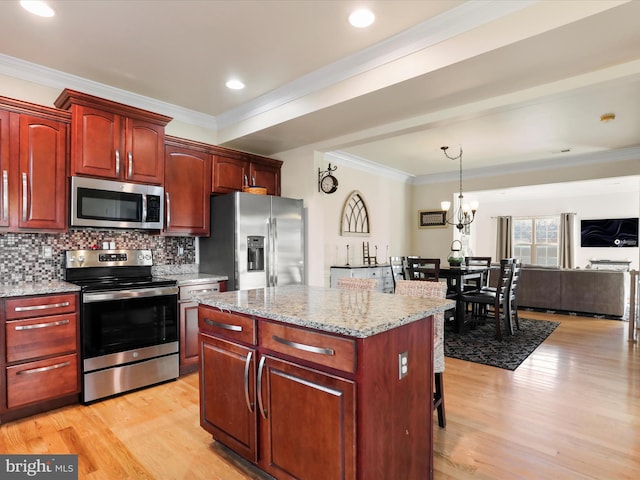 kitchen featuring appliances with stainless steel finishes, backsplash, a chandelier, a center island, and hanging light fixtures