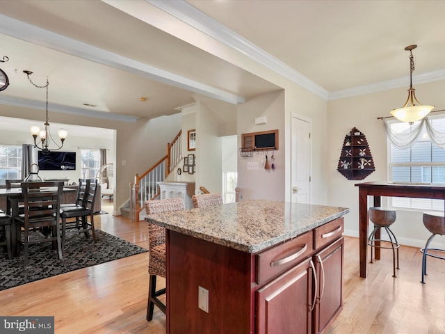 kitchen with crown molding, light hardwood / wood-style flooring, pendant lighting, and a notable chandelier