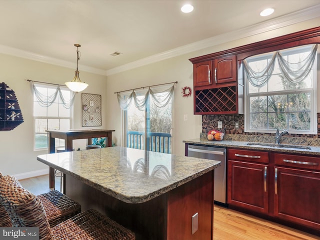 kitchen featuring sink, pendant lighting, light hardwood / wood-style flooring, dishwasher, and a center island