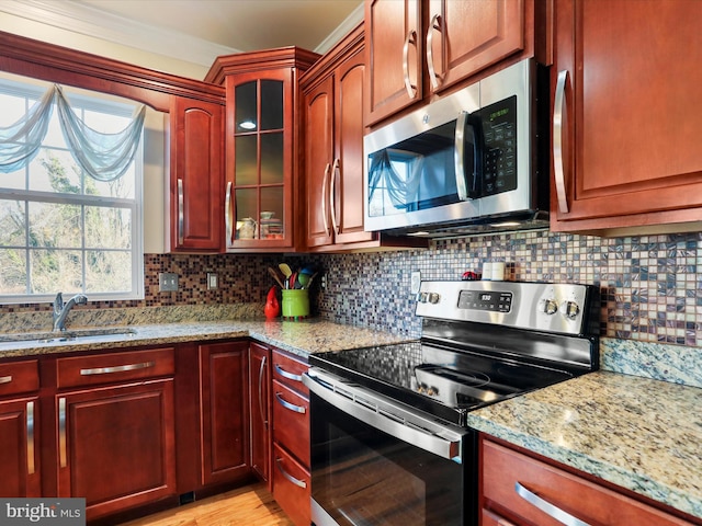 kitchen featuring decorative backsplash, light stone counters, sink, and appliances with stainless steel finishes