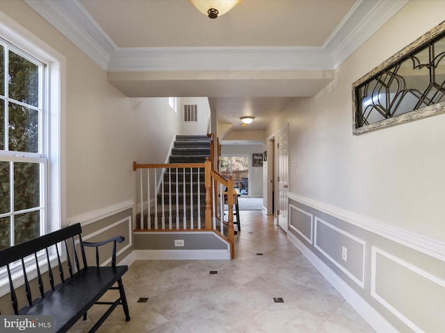 hall with plenty of natural light, light tile patterned floors, and ornamental molding