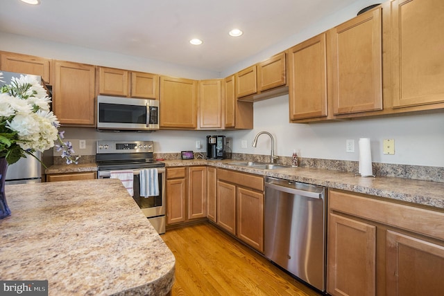 kitchen with sink, light wood-type flooring, and appliances with stainless steel finishes