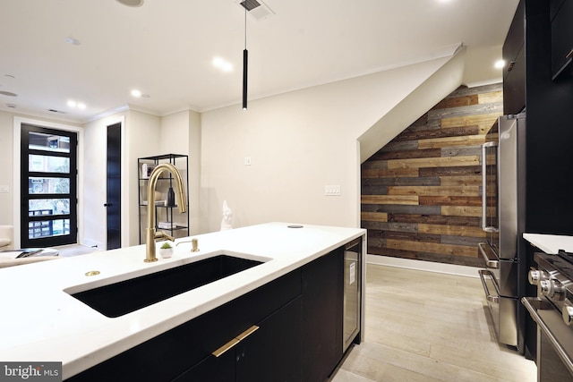 kitchen featuring pendant lighting, sink, wood walls, light wood-type flooring, and stainless steel range with gas stovetop