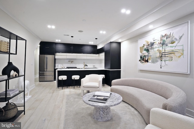 living room featuring crown molding, light hardwood / wood-style flooring, and sink