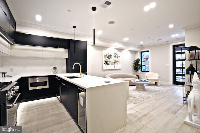 kitchen with decorative light fixtures, decorative backsplash, sink, light hardwood / wood-style flooring, and stainless steel appliances