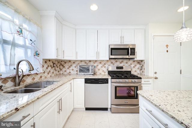 kitchen with backsplash, stainless steel appliances, sink, pendant lighting, and white cabinets