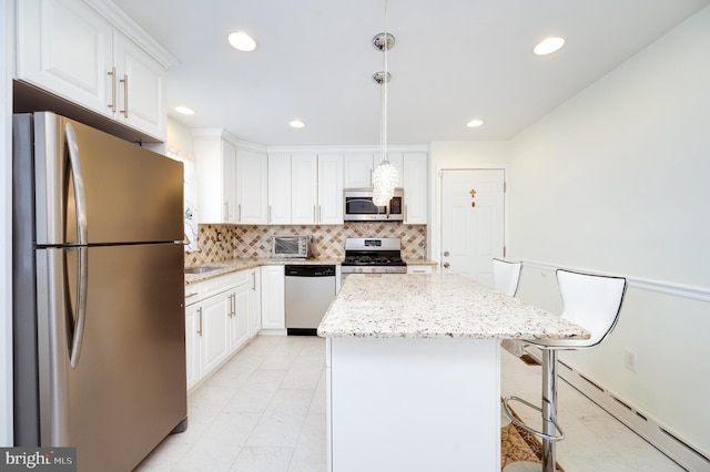 kitchen with a kitchen island, white cabinetry, stainless steel appliances, and hanging light fixtures