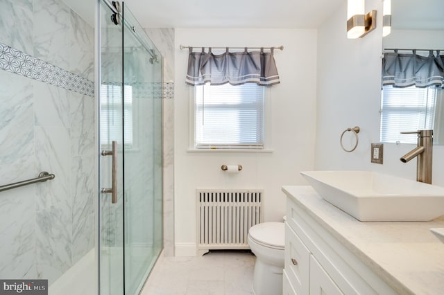 bathroom featuring vanity, a healthy amount of sunlight, toilet, and radiator