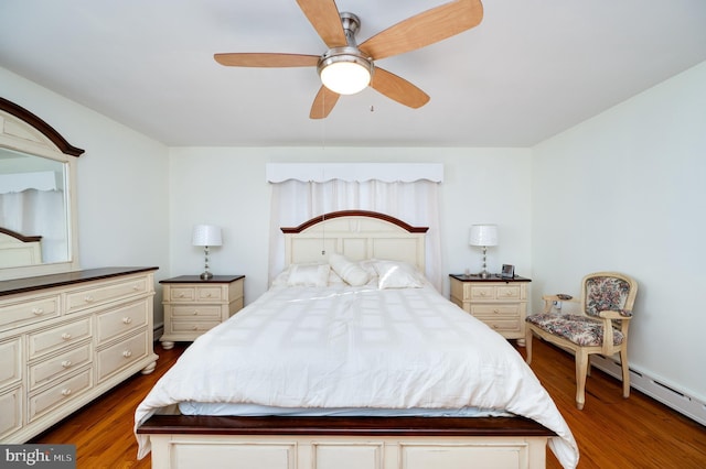 bedroom featuring ceiling fan, dark wood-type flooring, and a baseboard heating unit