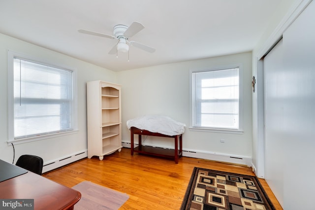 home office with baseboard heating, ceiling fan, and hardwood / wood-style flooring