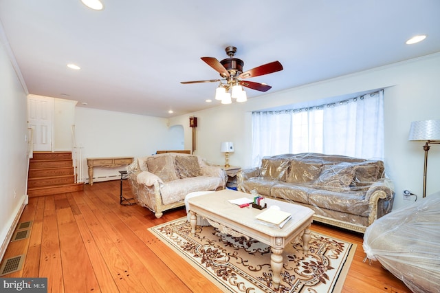 living room with ceiling fan, ornamental molding, baseboard heating, and light hardwood / wood-style flooring