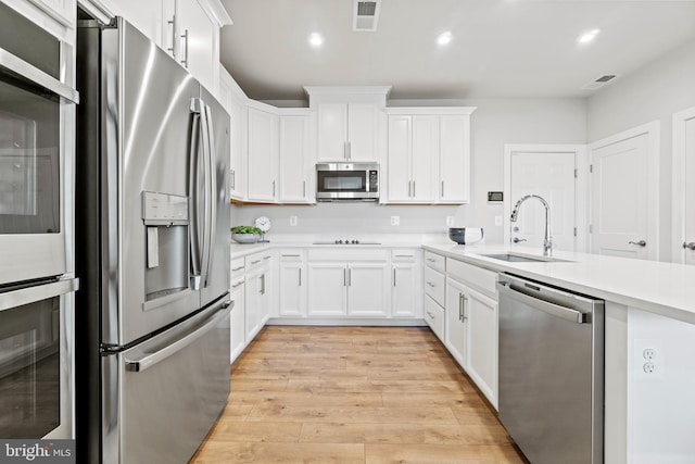 kitchen featuring white cabinetry, sink, stainless steel appliances, and light hardwood / wood-style flooring