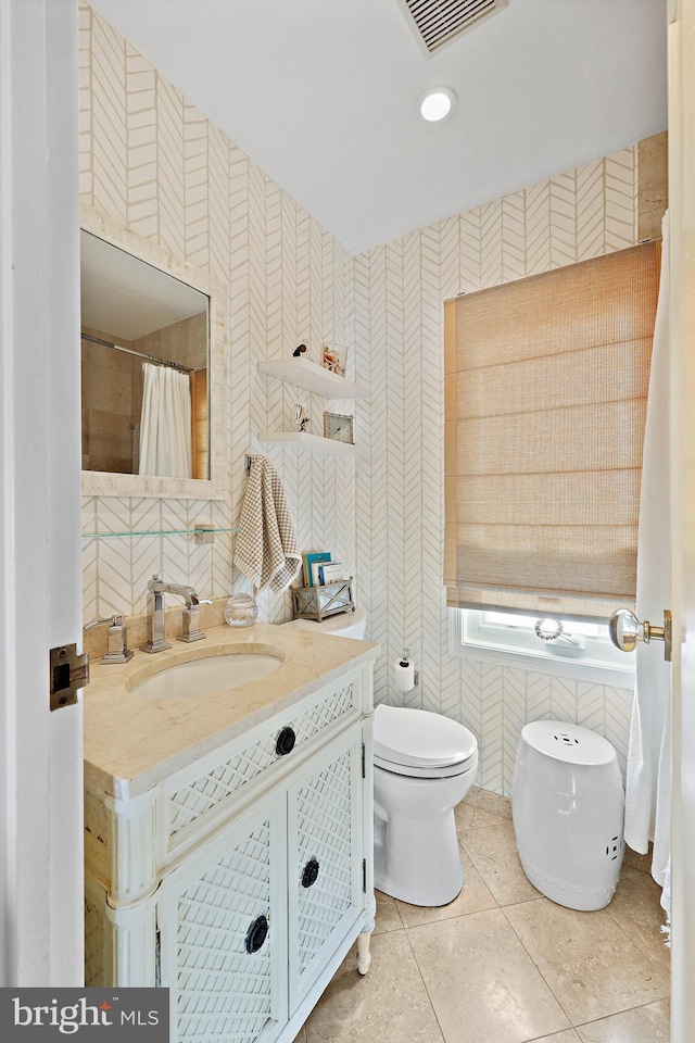 bathroom featuring tile patterned flooring, vanity, toilet, and tile walls