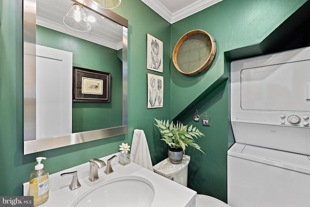 bathroom featuring stacked washer / dryer, toilet, vanity, and ornamental molding