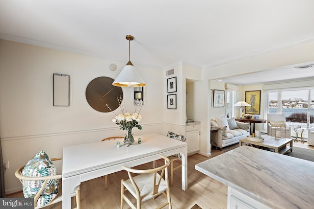 dining space featuring crown molding and light hardwood / wood-style flooring