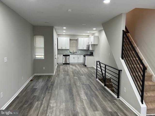 kitchen with decorative backsplash, dark wood-type flooring, white cabinets, and stainless steel appliances