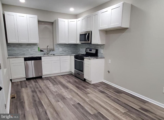 kitchen with sink, light wood-type flooring, light stone counters, white cabinetry, and stainless steel appliances