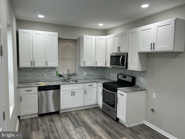 kitchen featuring sink, decorative backsplash, appliances with stainless steel finishes, light stone counters, and white cabinetry