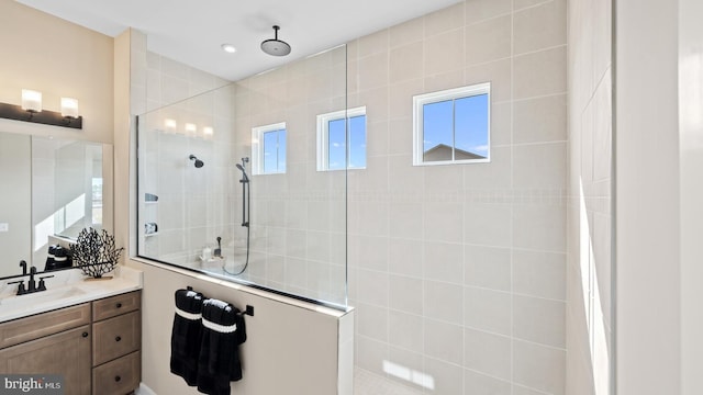 bathroom with tiled shower and vanity