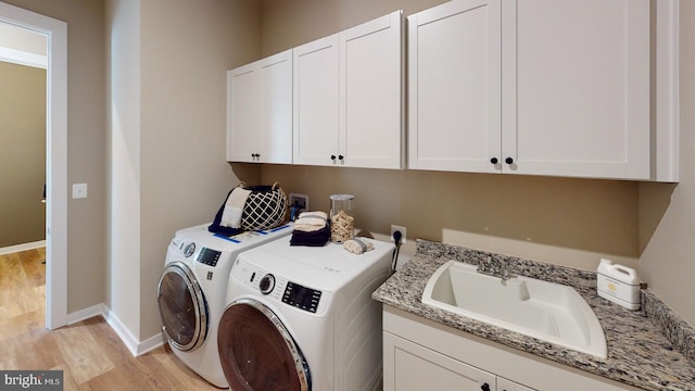 clothes washing area featuring light hardwood / wood-style floors, cabinets, independent washer and dryer, and sink