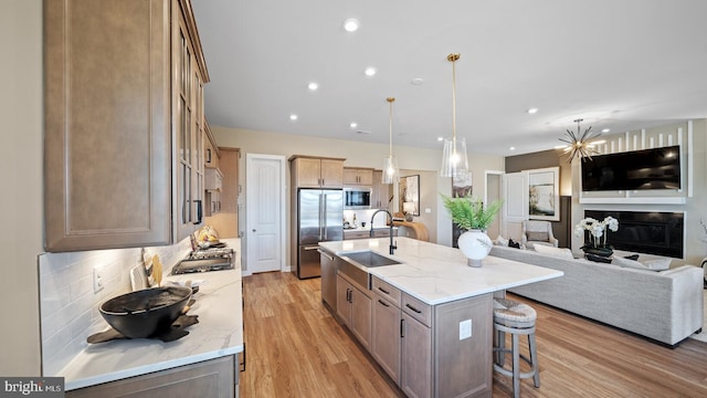 kitchen featuring sink, light stone countertops, a large island, light hardwood / wood-style floors, and stainless steel appliances