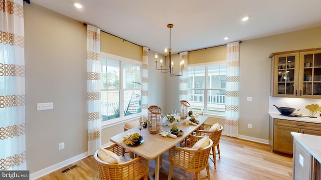 dining space with a notable chandelier, a healthy amount of sunlight, and light wood-type flooring