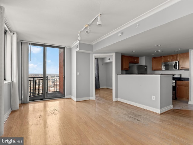 unfurnished living room featuring crown molding, expansive windows, track lighting, and light wood-type flooring