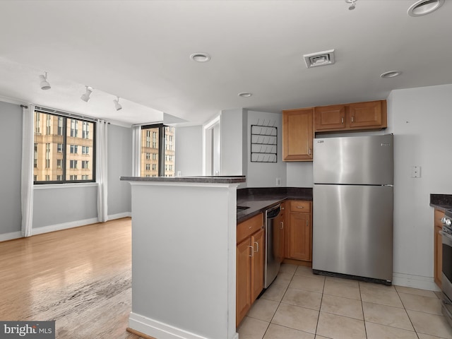 kitchen with light tile patterned floors, kitchen peninsula, rail lighting, and appliances with stainless steel finishes