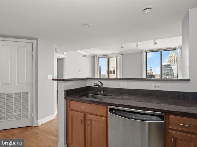 kitchen featuring dishwasher, a healthy amount of sunlight, dark stone countertops, and sink