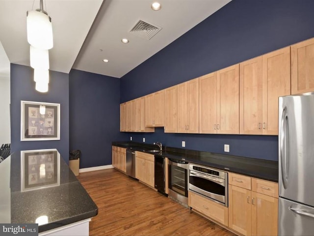 kitchen with sink, light brown cabinets, pendant lighting, and appliances with stainless steel finishes