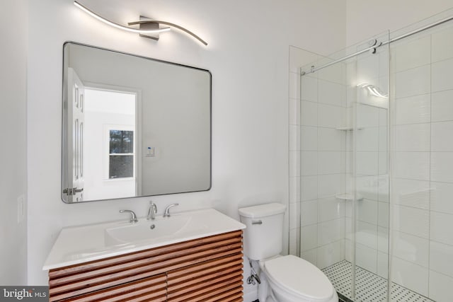 bathroom featuring vanity, a shower with shower door, and toilet