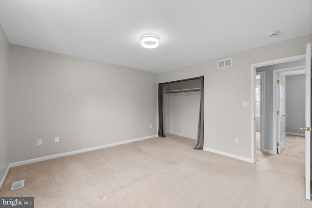 unfurnished bedroom featuring light carpet, baseboards, visible vents, and a closet