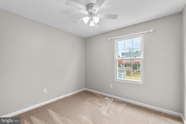 carpeted spare room featuring visible vents, ceiling fan, and baseboards