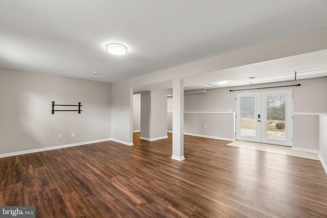 below grade area featuring baseboards, dark wood finished floors, and french doors