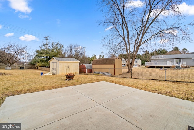 view of patio / terrace featuring a storage shed, a fenced backyard, an outdoor fire pit, and an outdoor structure