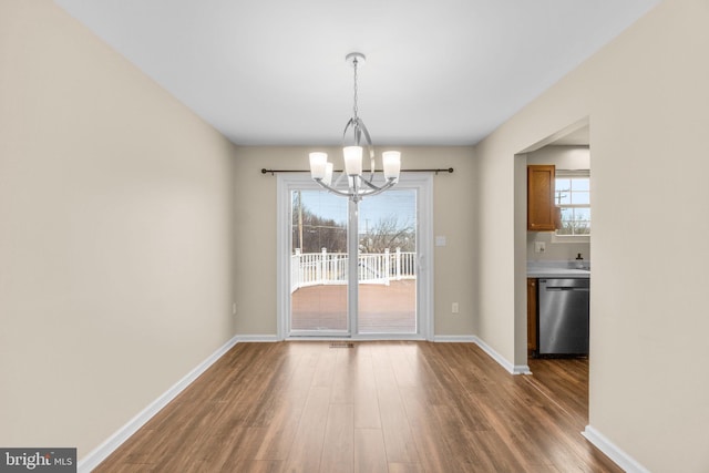 unfurnished dining area featuring a notable chandelier, visible vents, baseboards, and wood finished floors