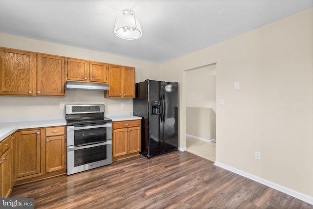 kitchen featuring under cabinet range hood, black fridge with ice dispenser, light countertops, double oven range, and brown cabinets